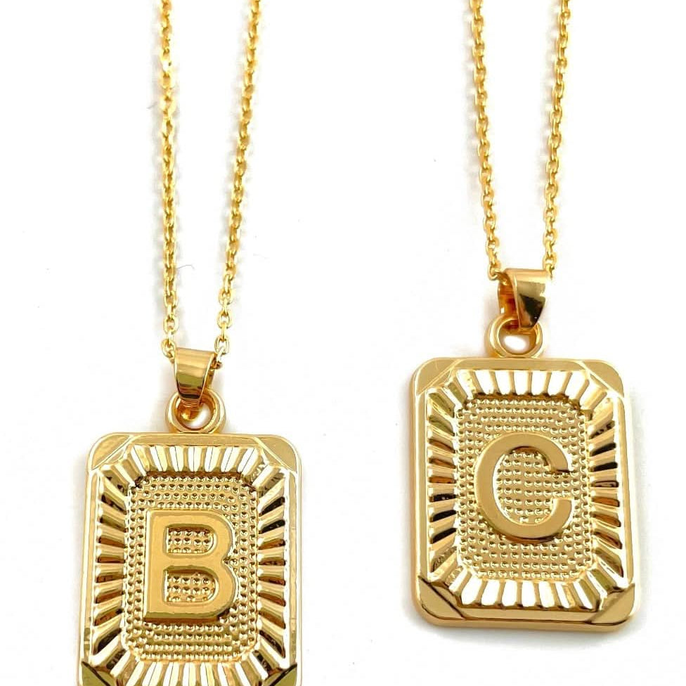Letter B and C tarnish free gold initial charm necklaces behind a blank background.