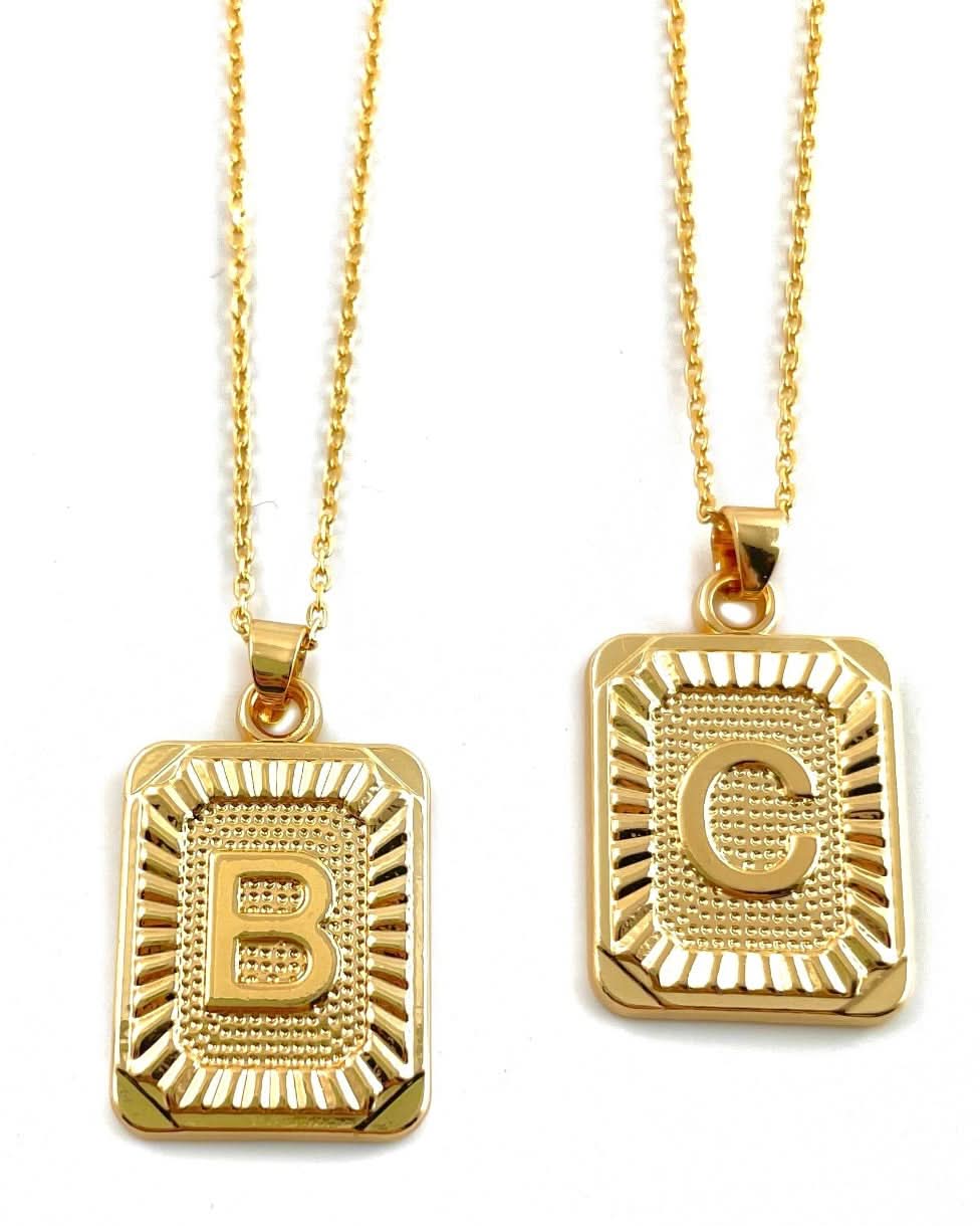 Letter B and C tarnish free gold initial charm necklaces behind a blank background.