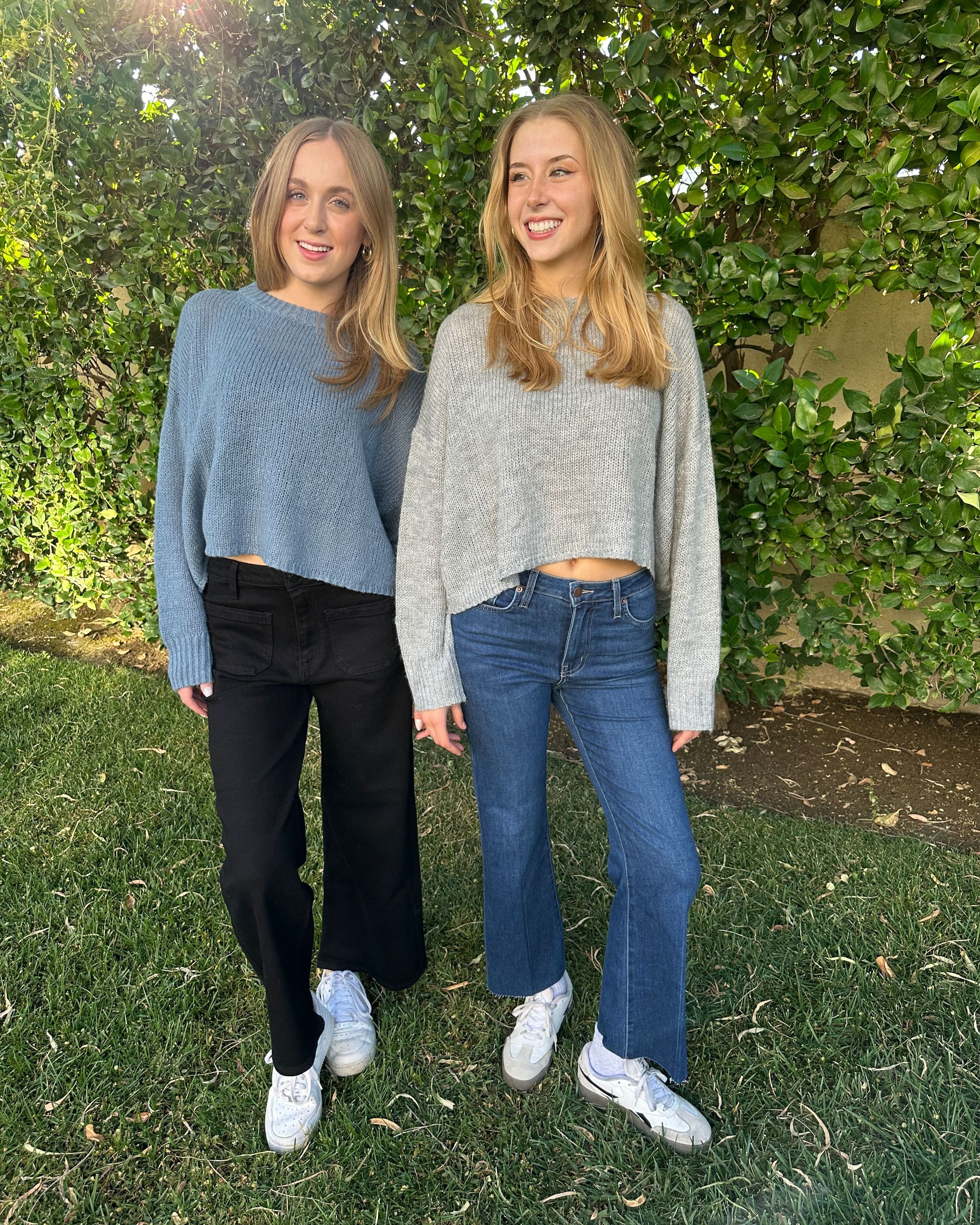 Two people standing on grass with trees