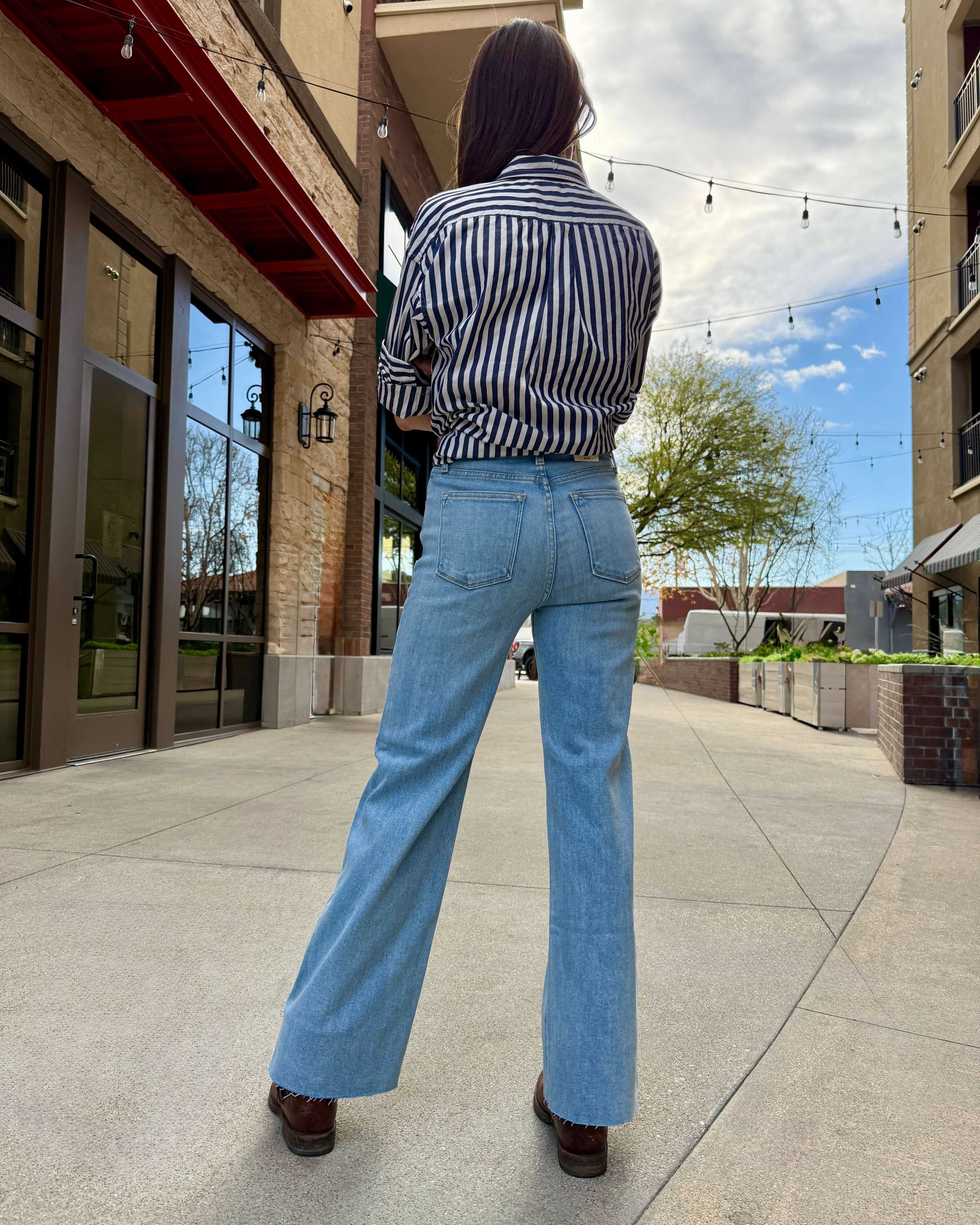 Woman wearing light wash raw hem jeans with navy blue