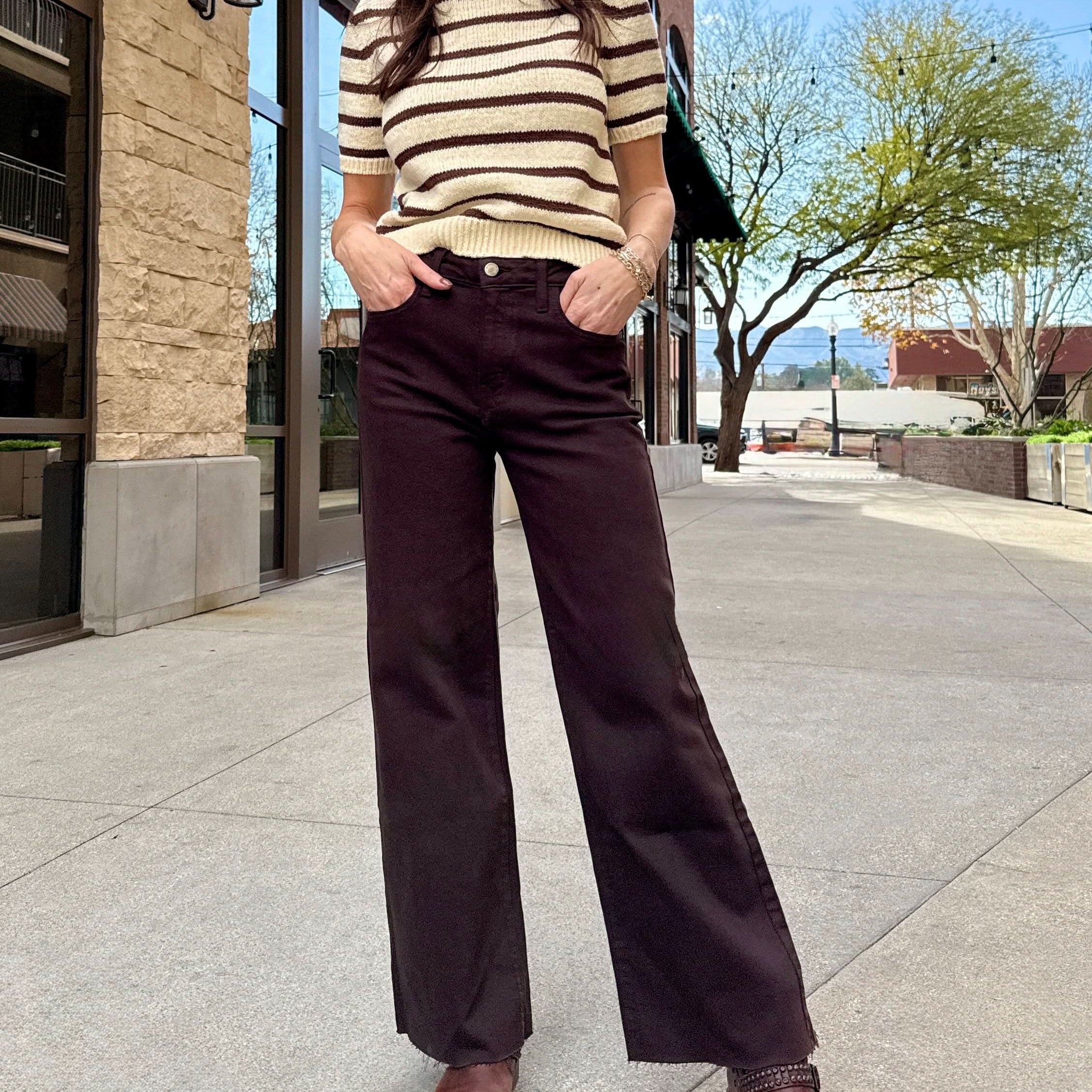 Woman wearing brown raw hem jeans with stripe cream and brown stripped sweater.