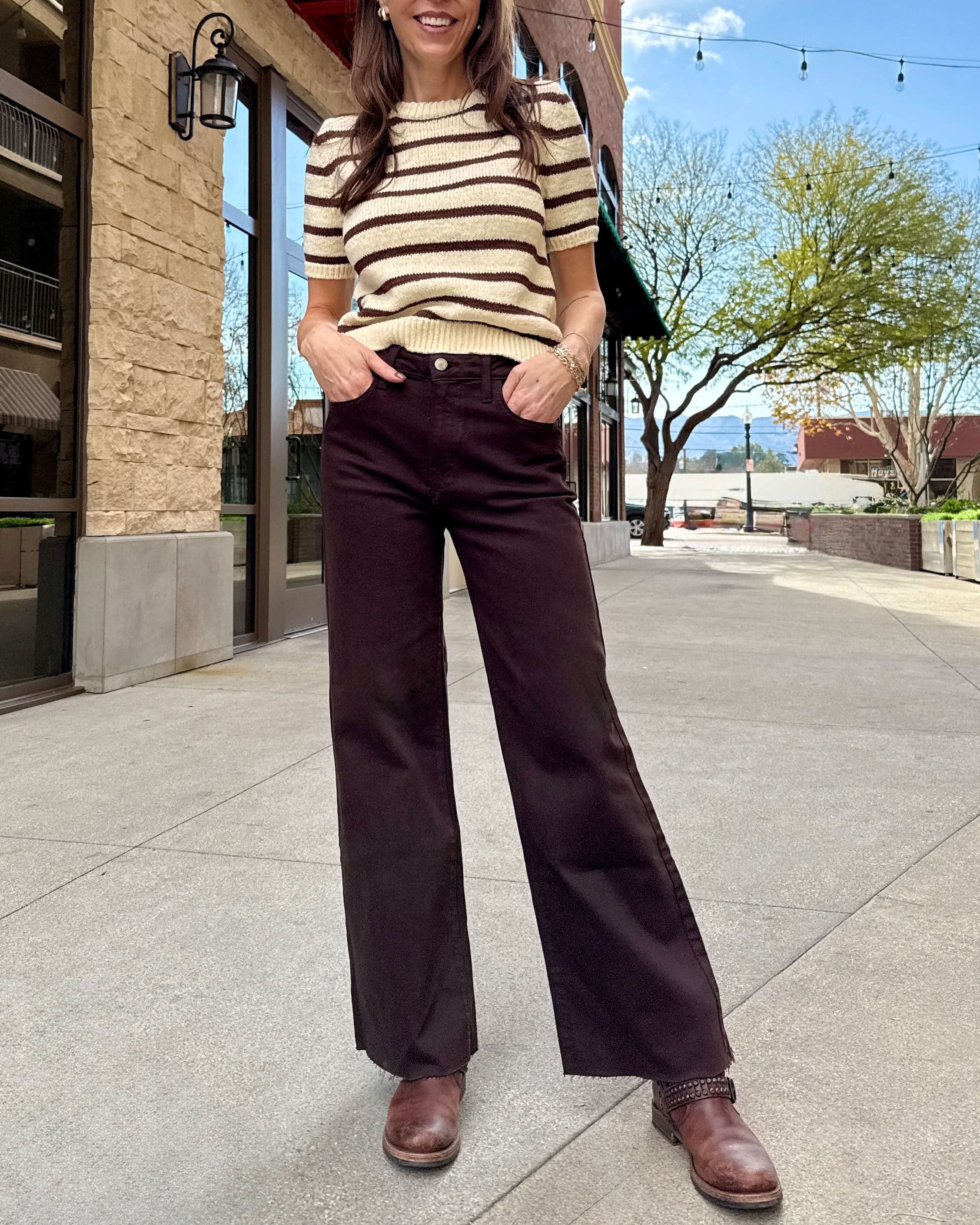 Woman wearing brown raw hem jeans with stripe cream and brown stripped sweater.