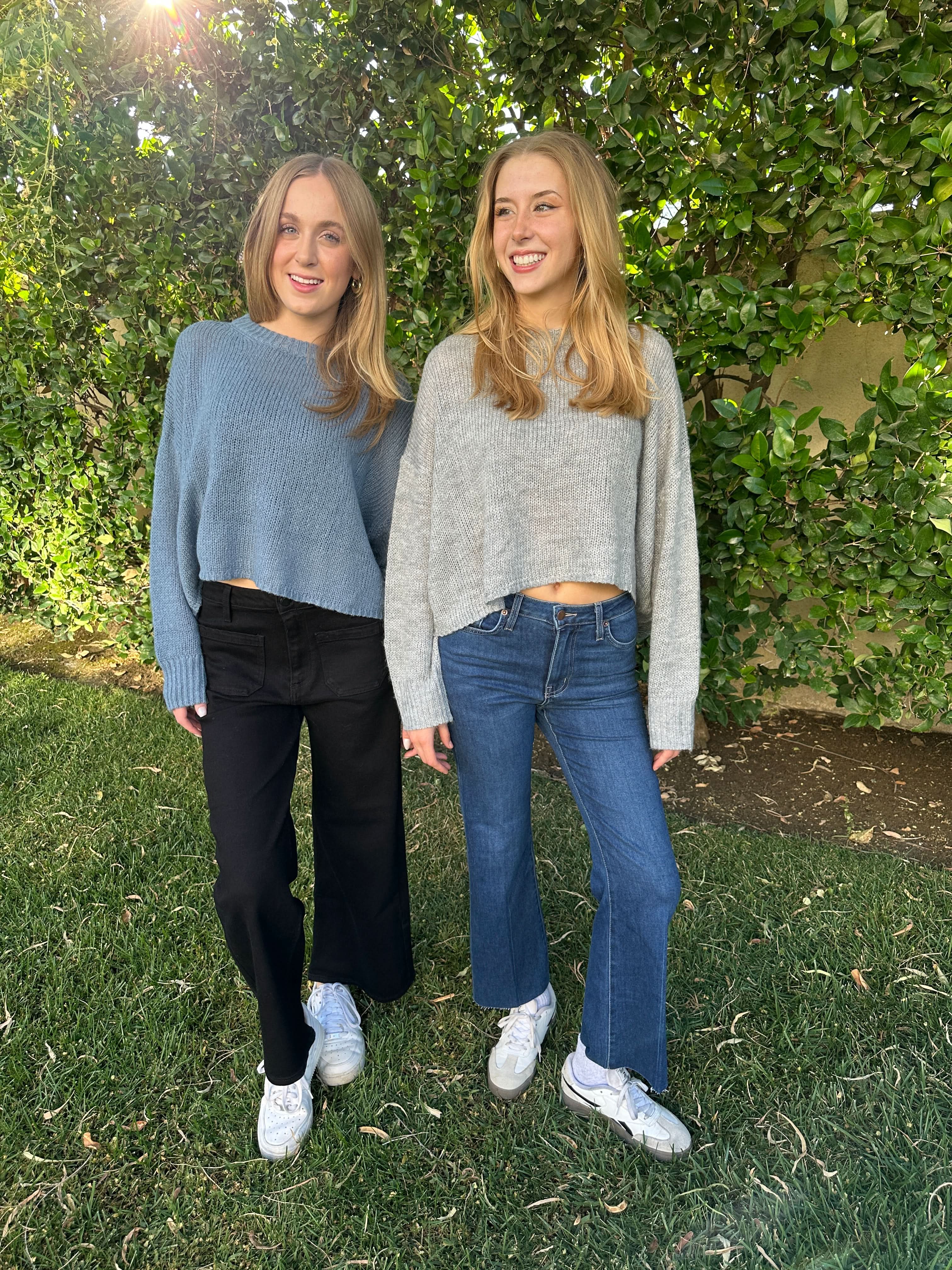 Two people standing on grass with trees in the background