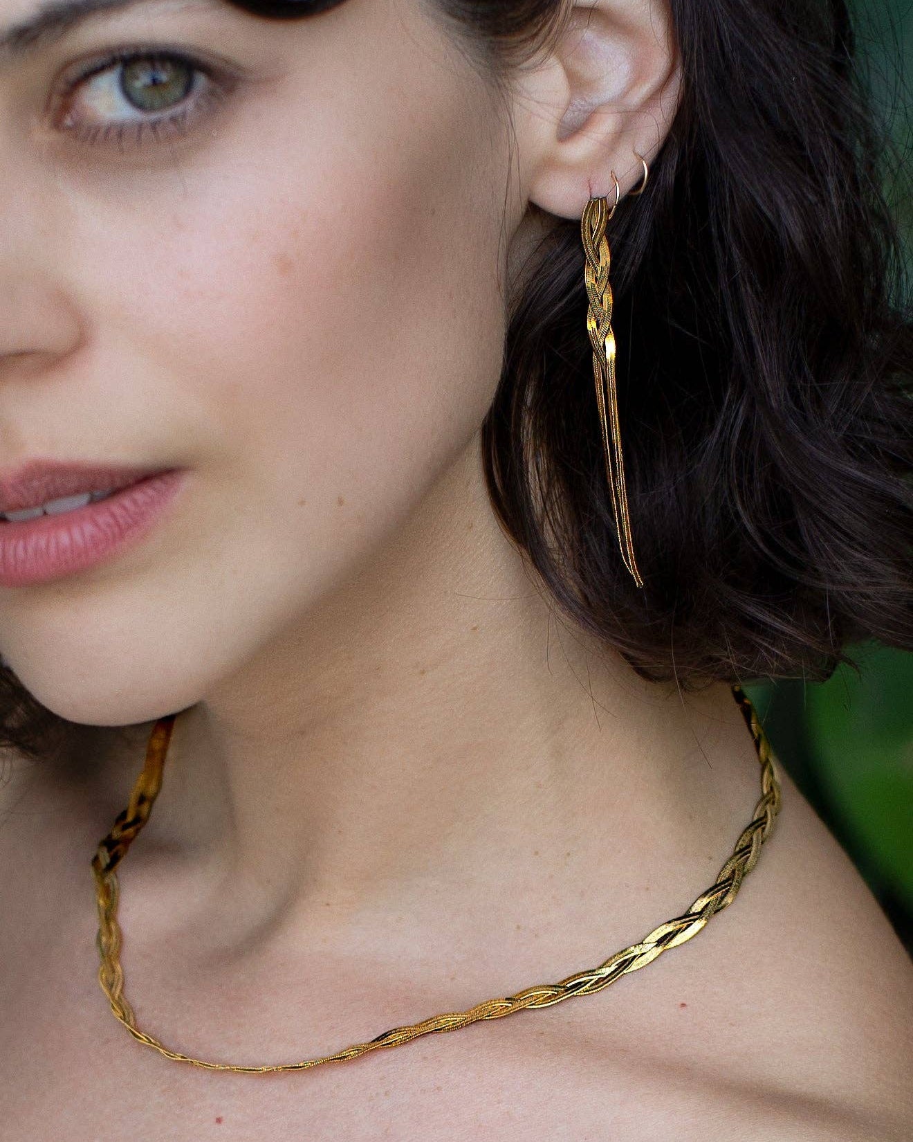 Close-up of a woman wearing gold hoop earrings and a gold necklace.