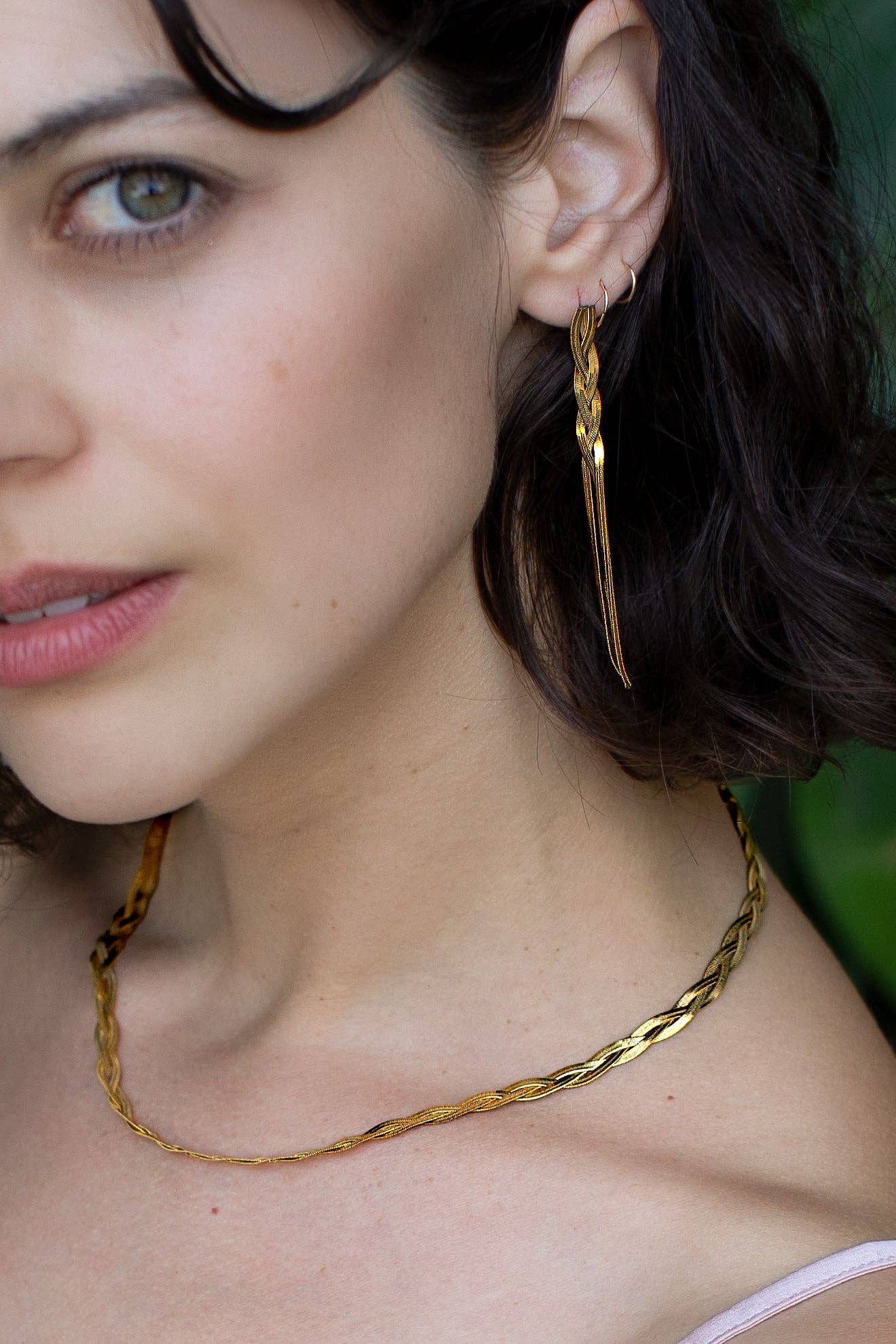 Close-up of a woman wearing gold hoop earrings and a gold necklace.