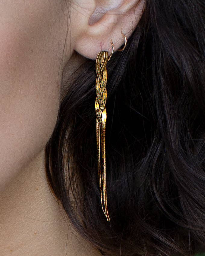 Gold earrings worn by a person with dark hair.