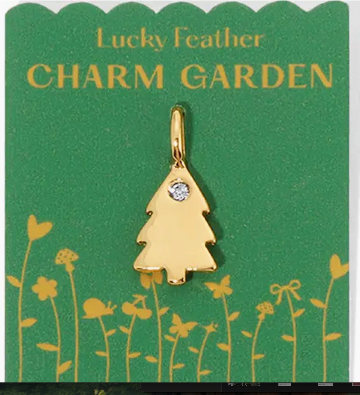 Gold tree-shaped charm with a diamond on a 'Lucky Feather Charm Garden' card with green background and floral designs.
