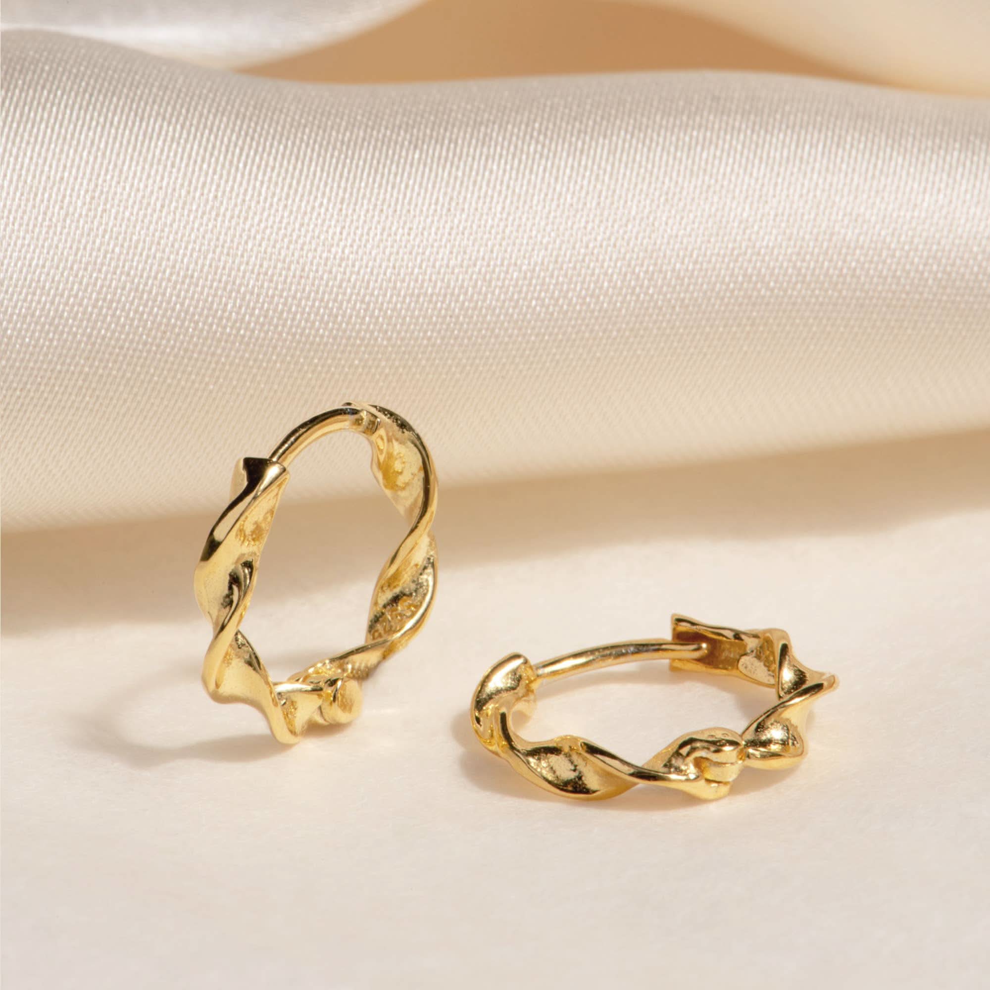 MAIVE Olive Hoop Earrings Gold hoop earrings on a beige fabric background
