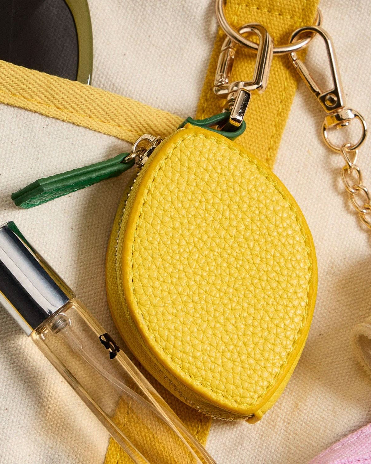 Yellow lemon-shaped pouch with a keychain on a beige background