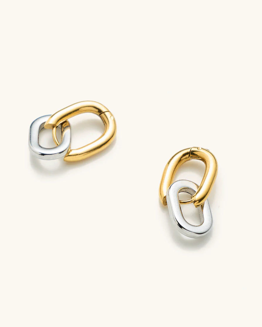 Pair of gold and silver interlocking ring earrings laying on a white background