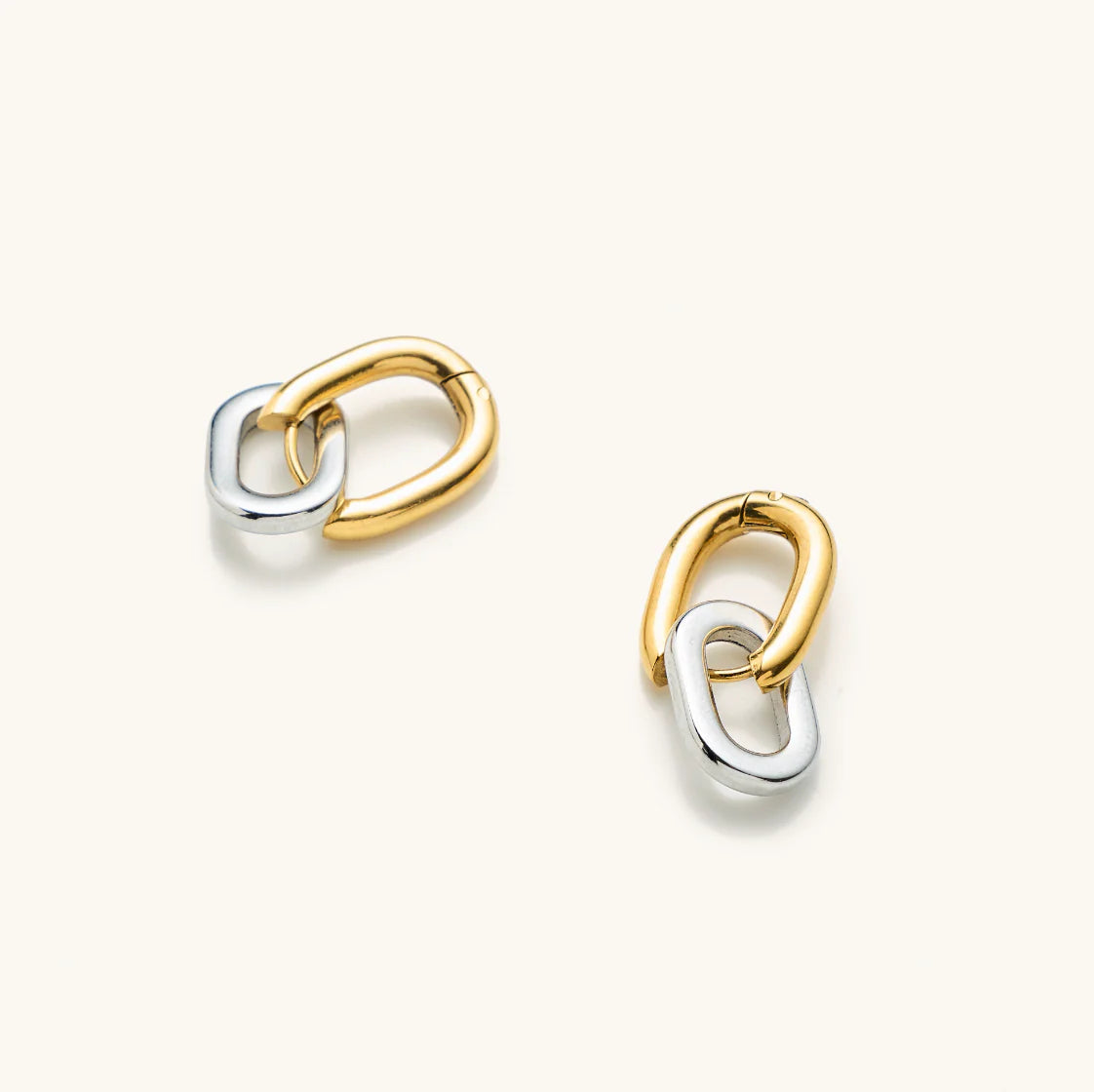Pair of gold and silver interlocking ring earrings laying on a white background