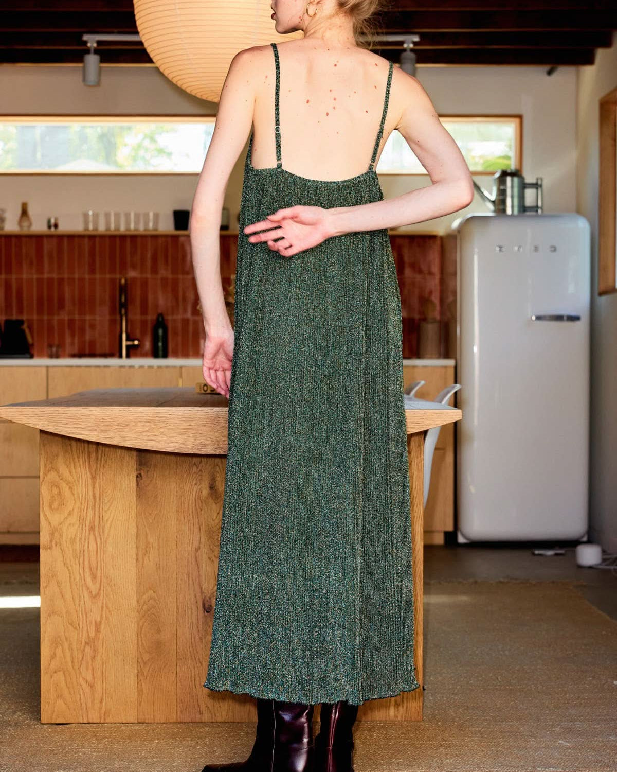 Olive Metallic Camisole Midi Dress Woman in a green dress standing in a kitchen