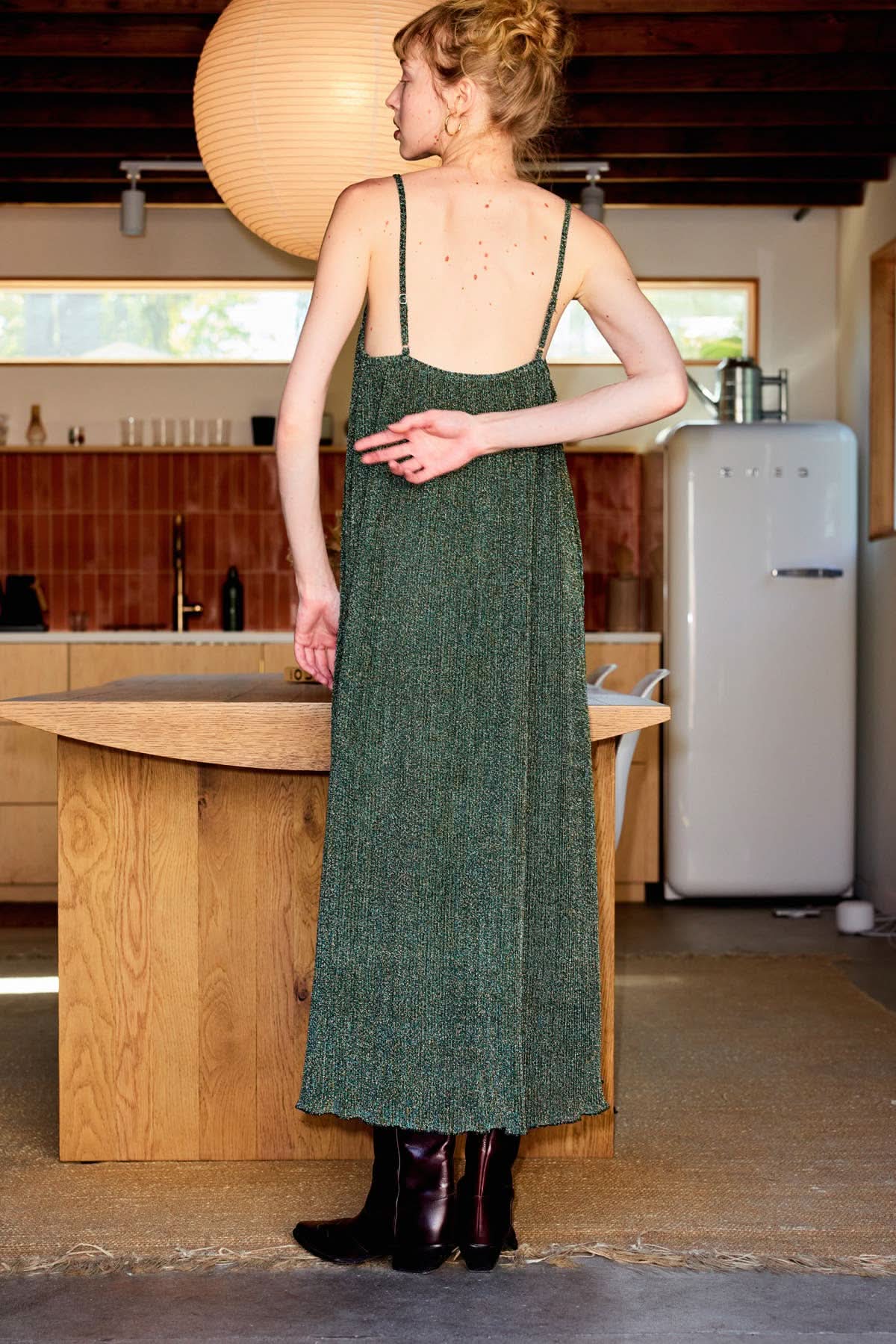 Olive Metallic Camisole Midi Dress Woman in a green dress standing in a kitchen