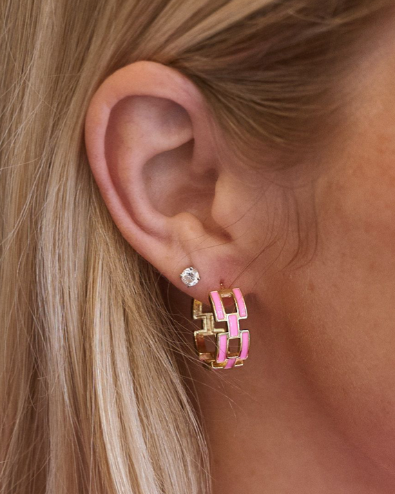 Close-up of an ear wearing a pink and gold geometric hoop earring.