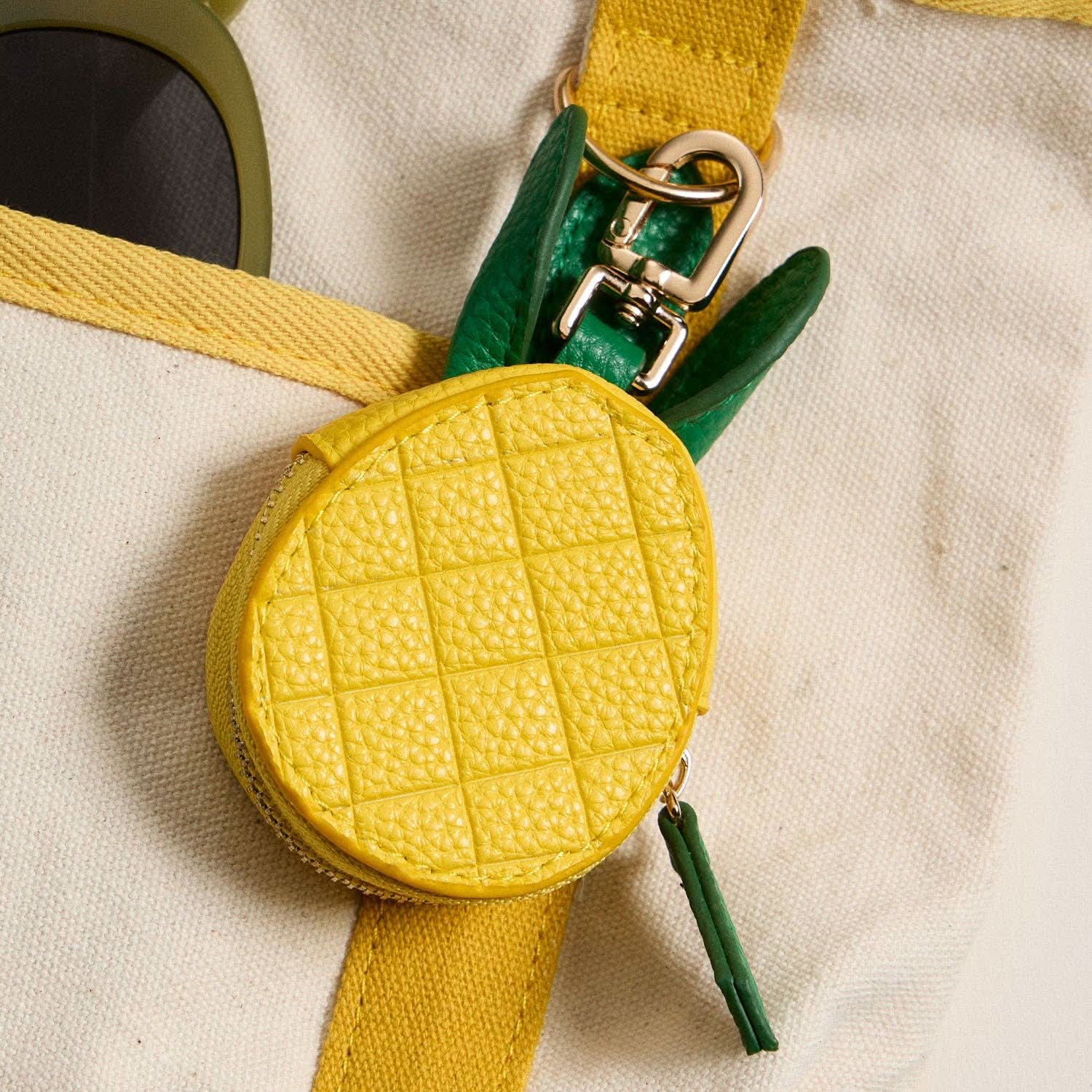 Yellow textured pouch with green strap on a beige background