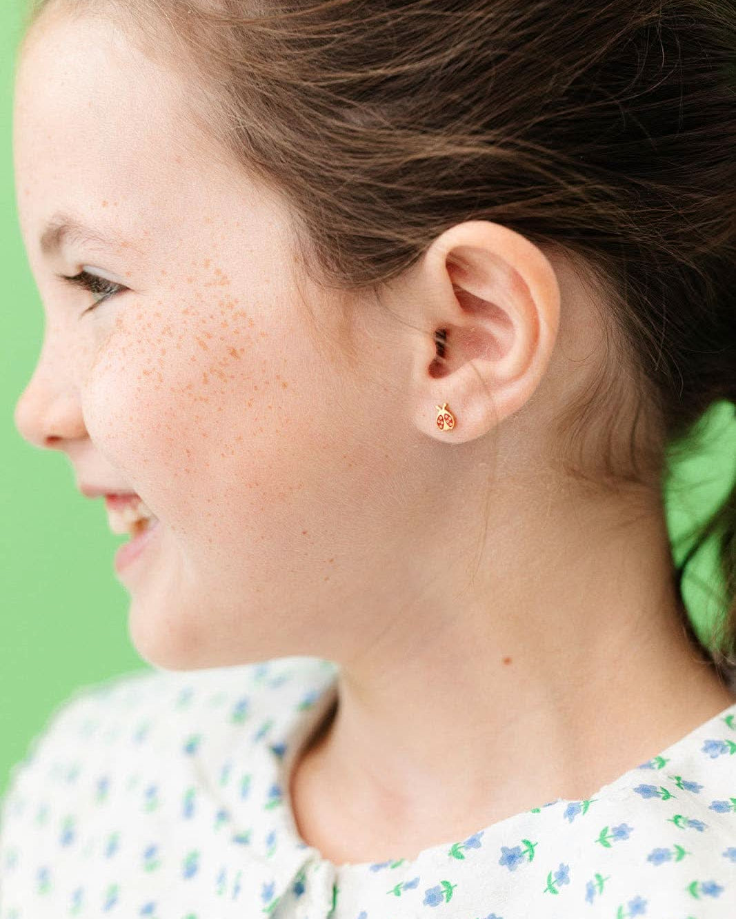Child wearing a Pair of red and gold ladybug flat back earrings