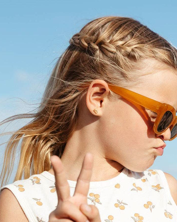 Young girl wearing orange sunglasses with a clear blue sky