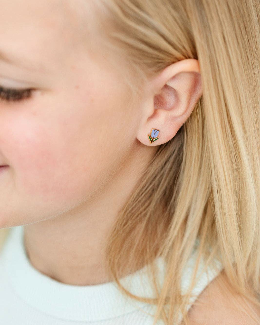 Close-up of a child wearing a small earring with a butterfly design.