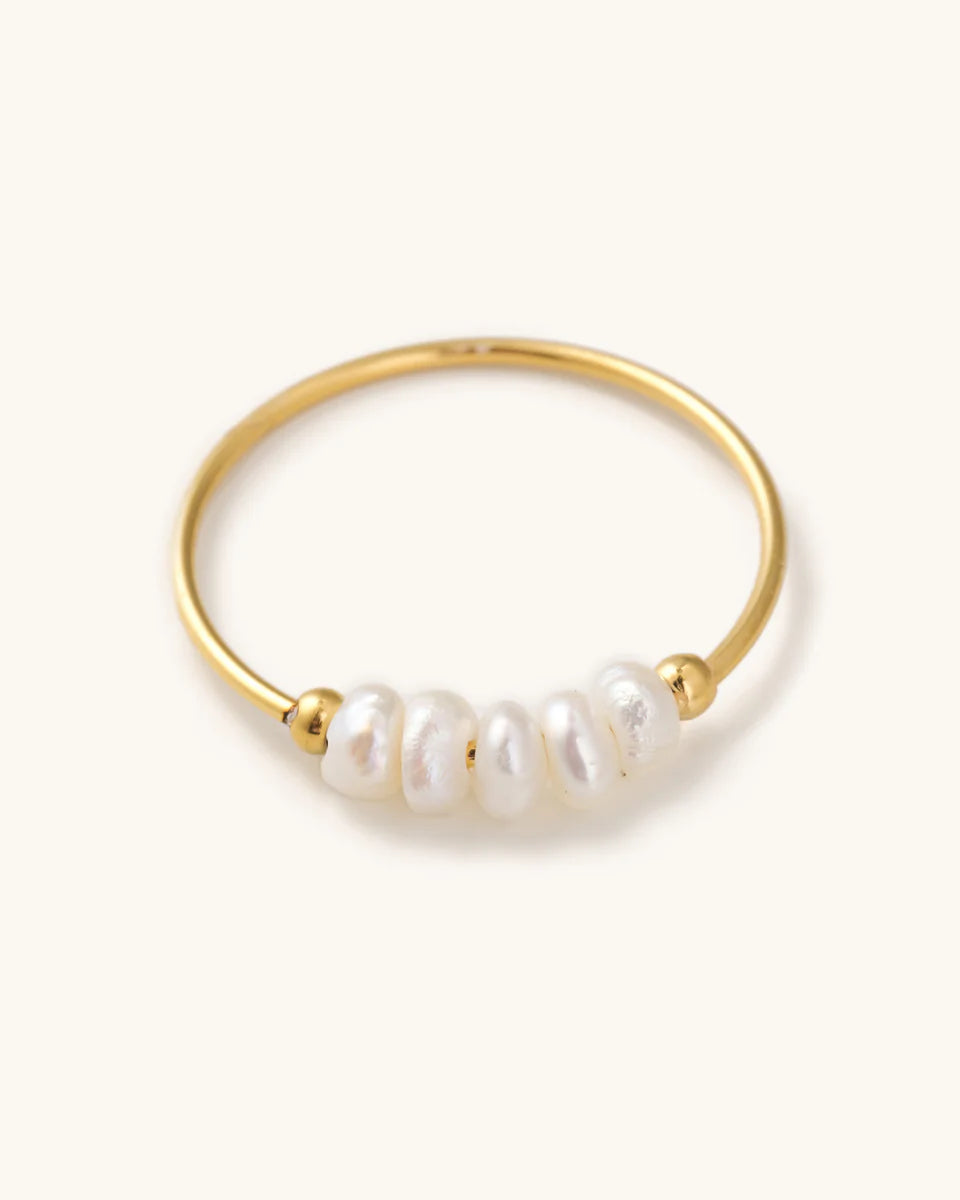Simple, thin, Gold ring with multiple pearls laying on a white background