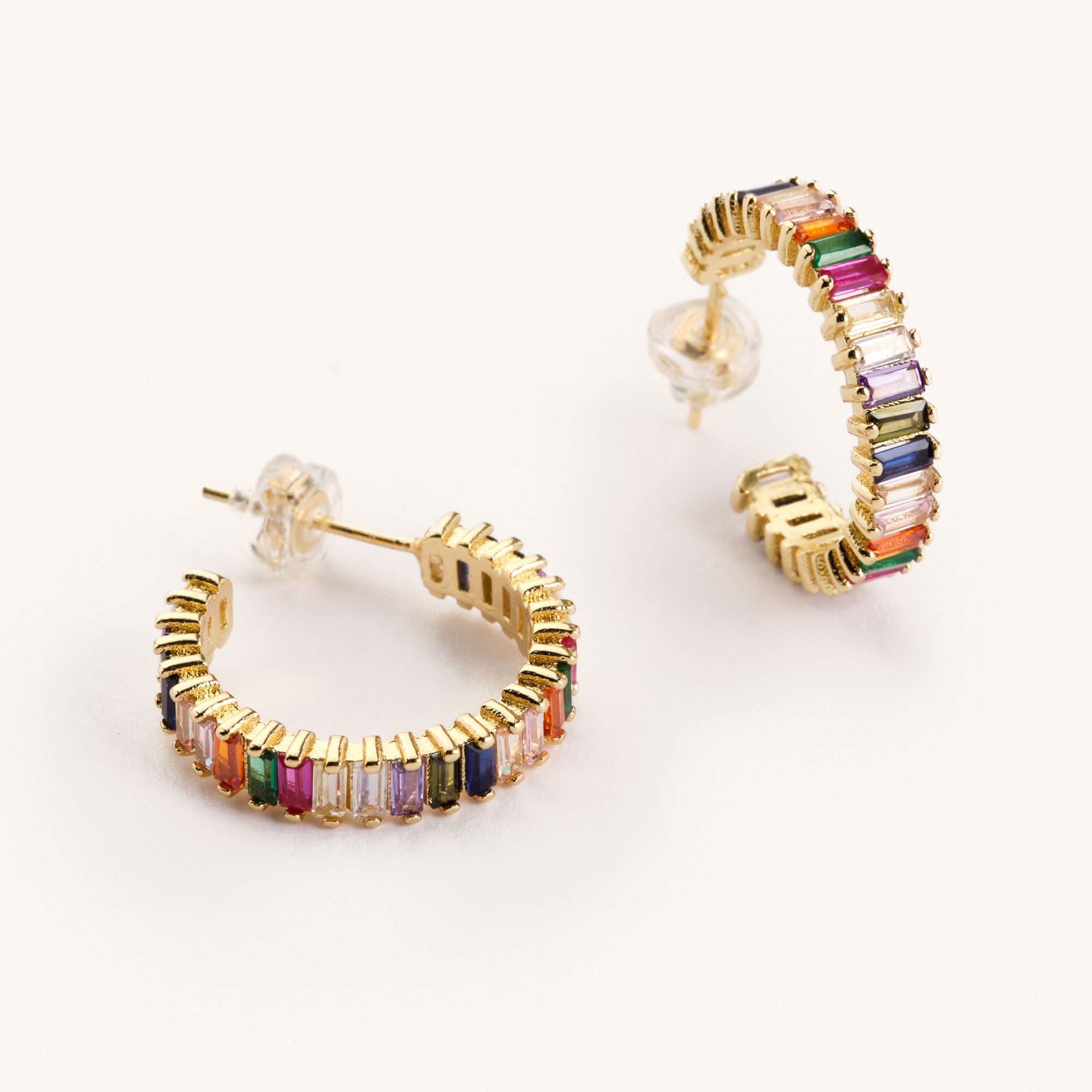 Rainbow colored shimmer hoop earrings laying on a white background