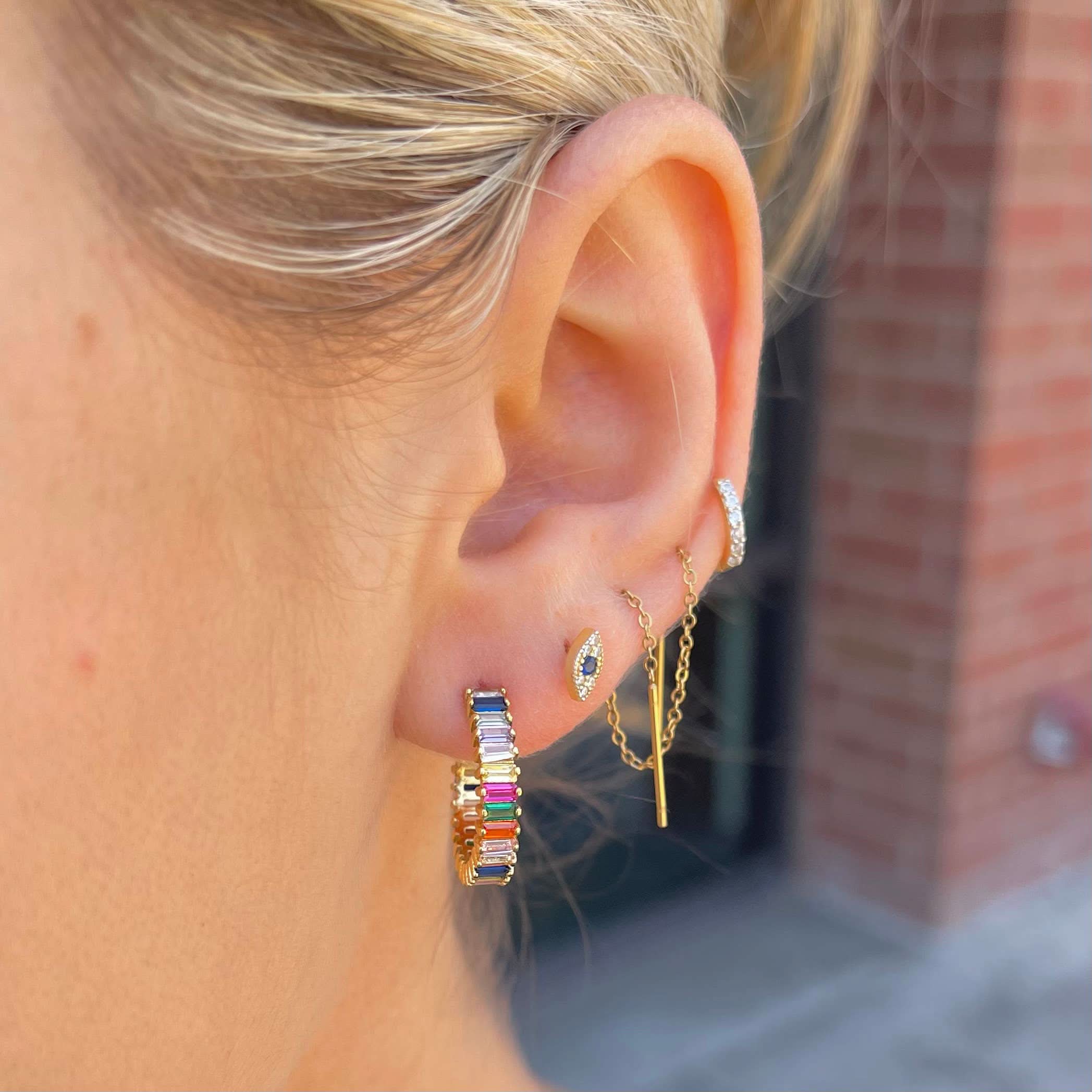 Woman wearing earrings including Rainbow colored shimmer hoop earrings