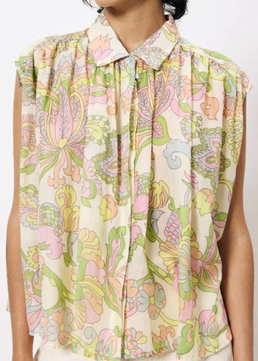 Zoomed in on woman wearing sleeveless pastel floral flowing blouse