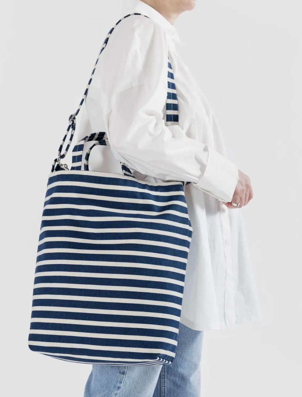 Woman carrying Blue and white horizontally striped duck bag from BAGGU
