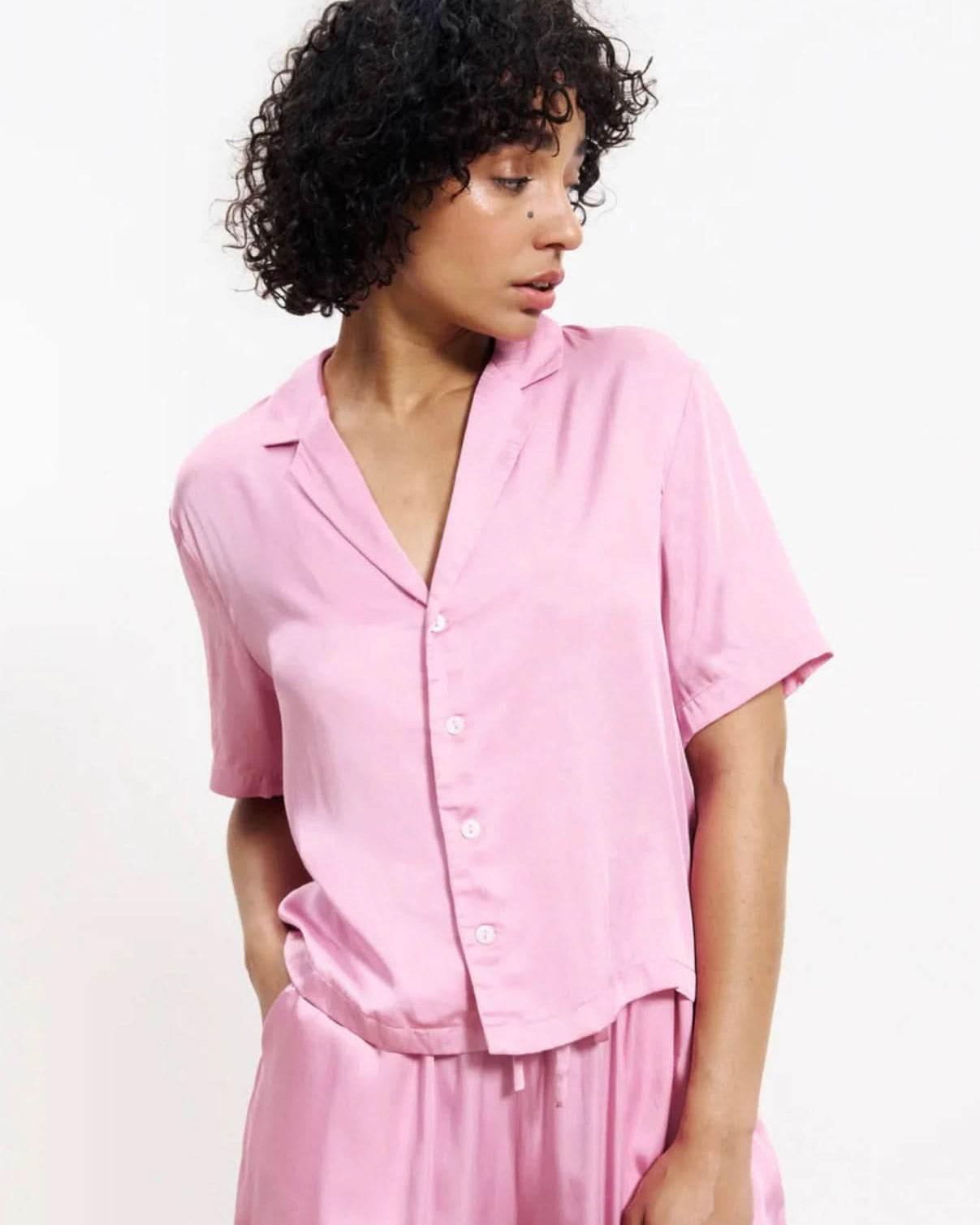 Woman wearing a pink silky blouse button up with matching pants