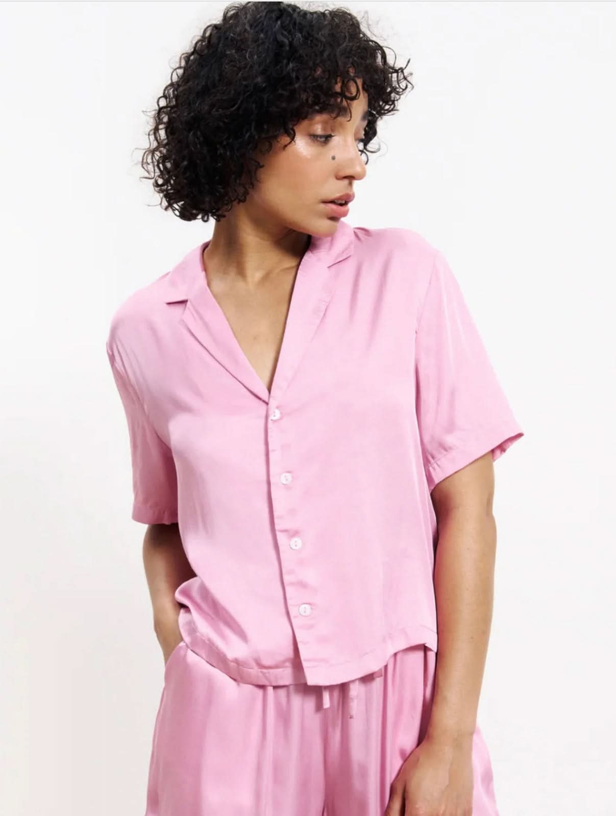 Woman wearing a pink silky blouse button up with matching pants