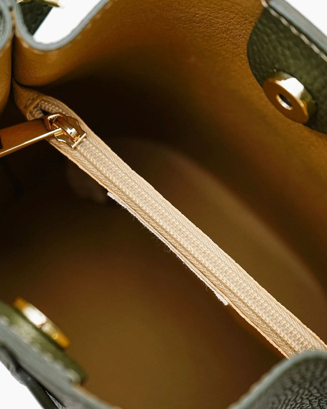 Close-up of a leather handbag with gold zipper and stitching.