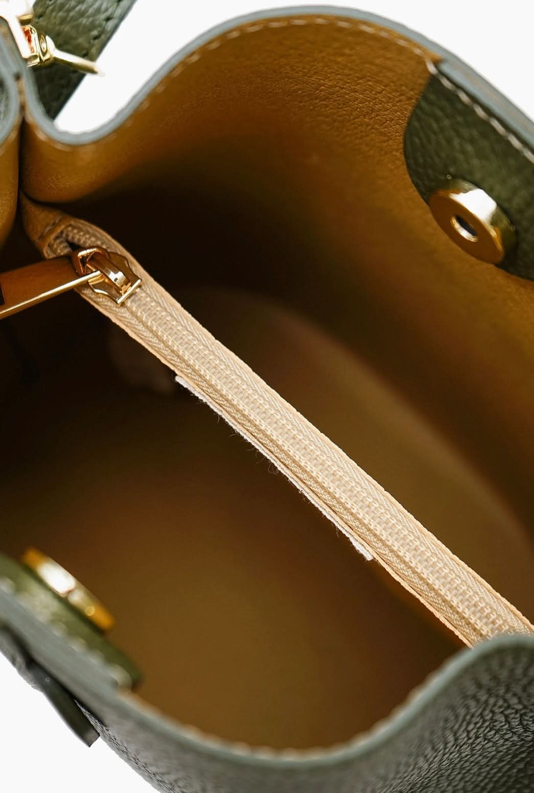 Close-up of a leather handbag with gold zipper and stitching.