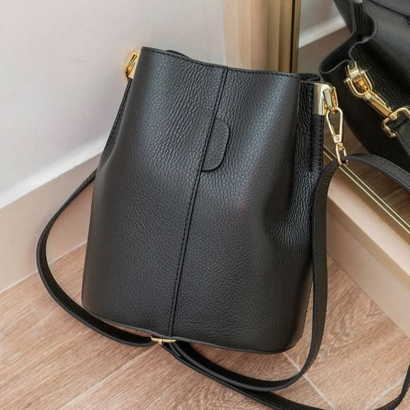 Black leather handbag with gold accents on a wooden floor