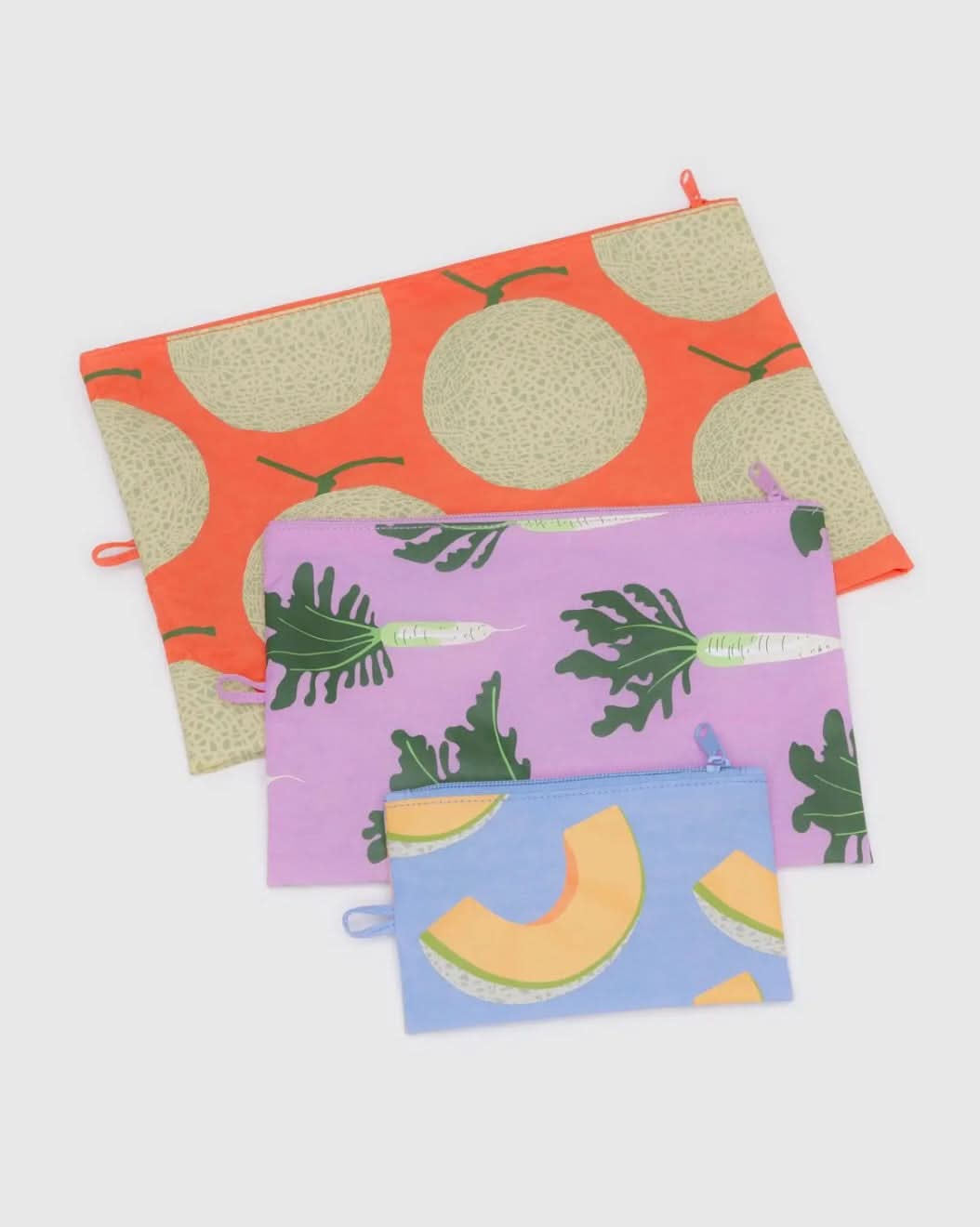 Three BAGGU travel pouch bags in varying sizes the largest is orange and pictures cantaloupes, the medium pouch is purple and pictures carrots, the smallest pouch is blue with sliced cantaloupe