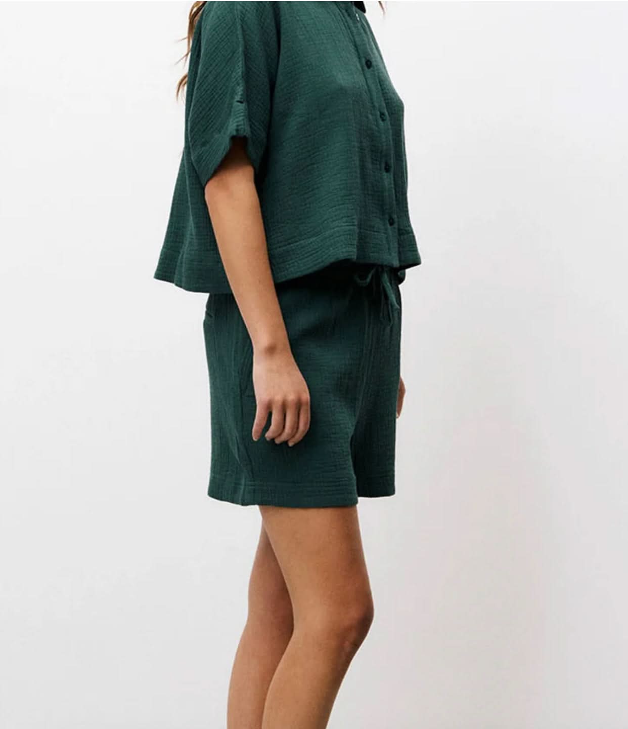 Side view of Woman wearing matching dark Forrest green, shorts and short-sleeve set