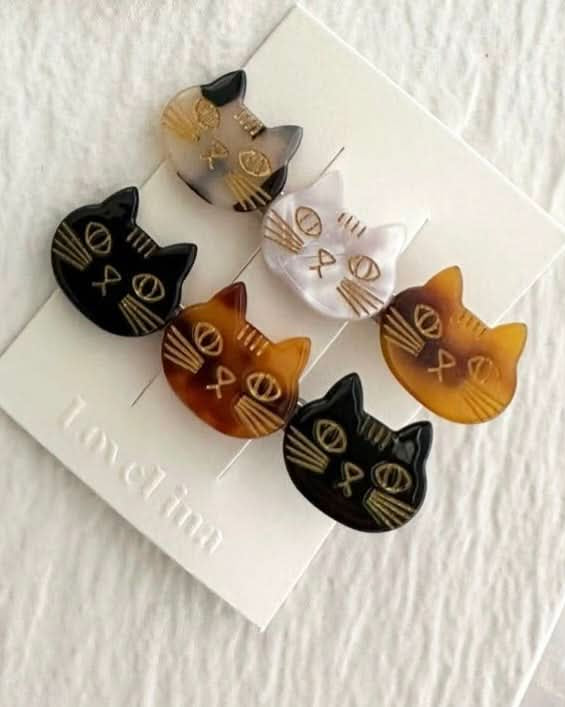 A pair of three colorful cats on a clip in a pack of two behind a white background.