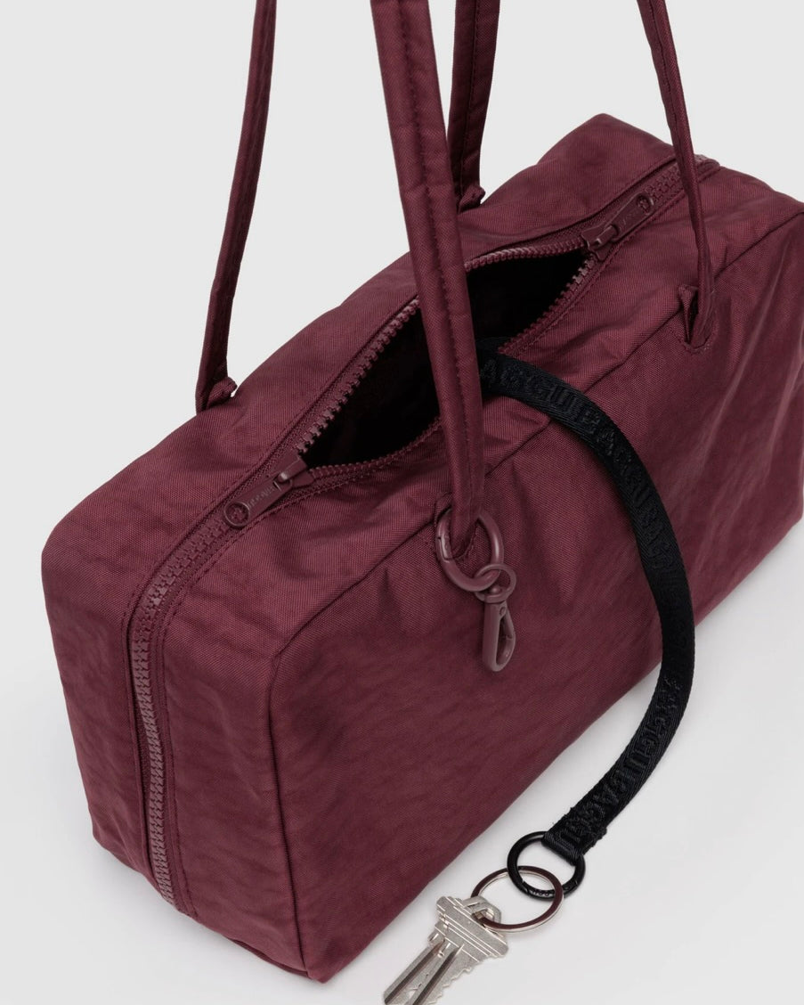 Maroon BAGGU bowler bag with a keychain on a white background