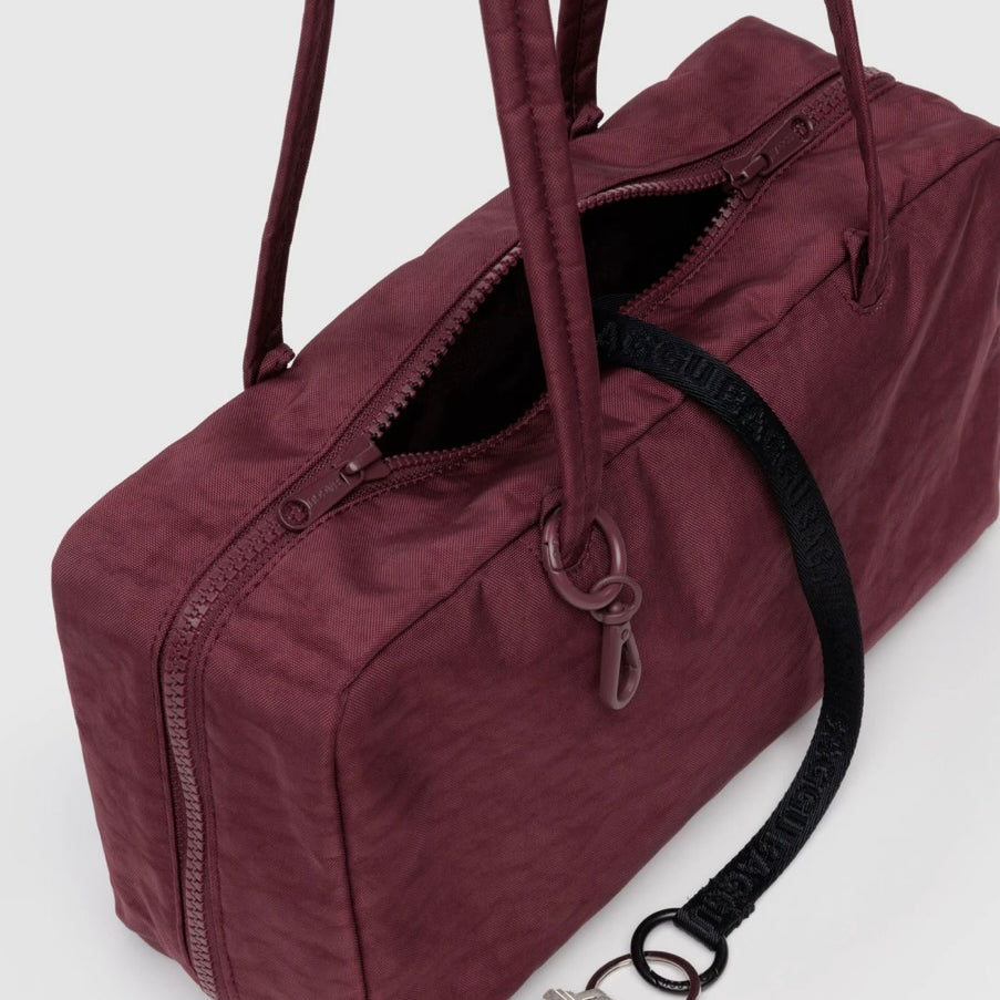 Maroon BAGGU bowler bag with a keychain on a white background