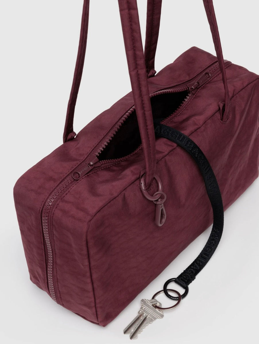 Maroon BAGGU bowler bag with a keychain on a white background
