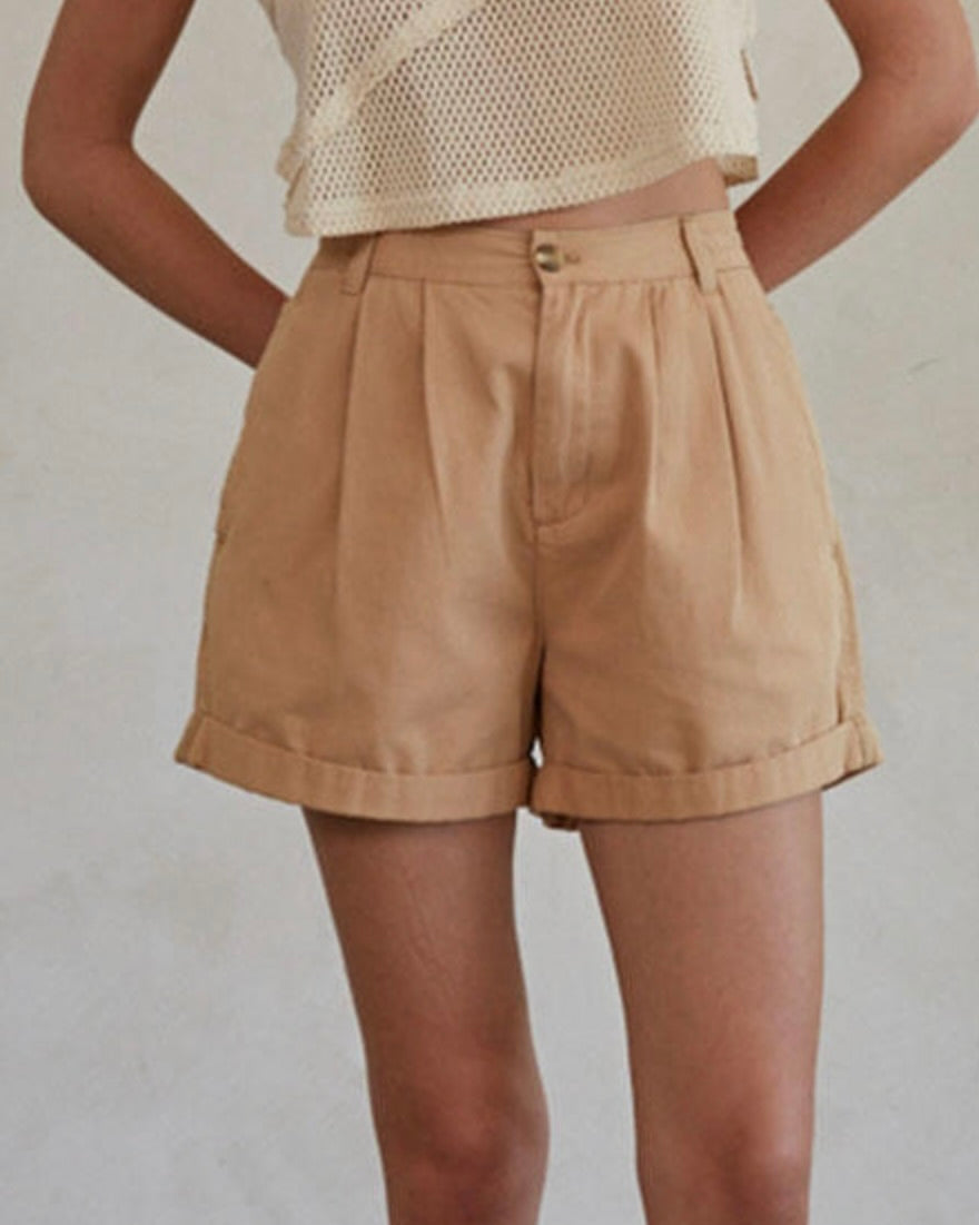 Person wearing beige shorts on a plain background