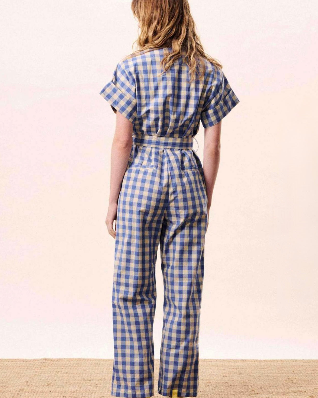 Person wearing a blue and white checkered jumpsuit on a plain background