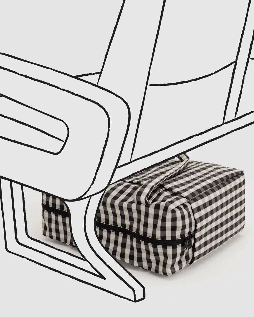 A black and white gingham check toiletry bag with a black zipper, shown under a minimalist black line drawing of a chair on a light gray background.