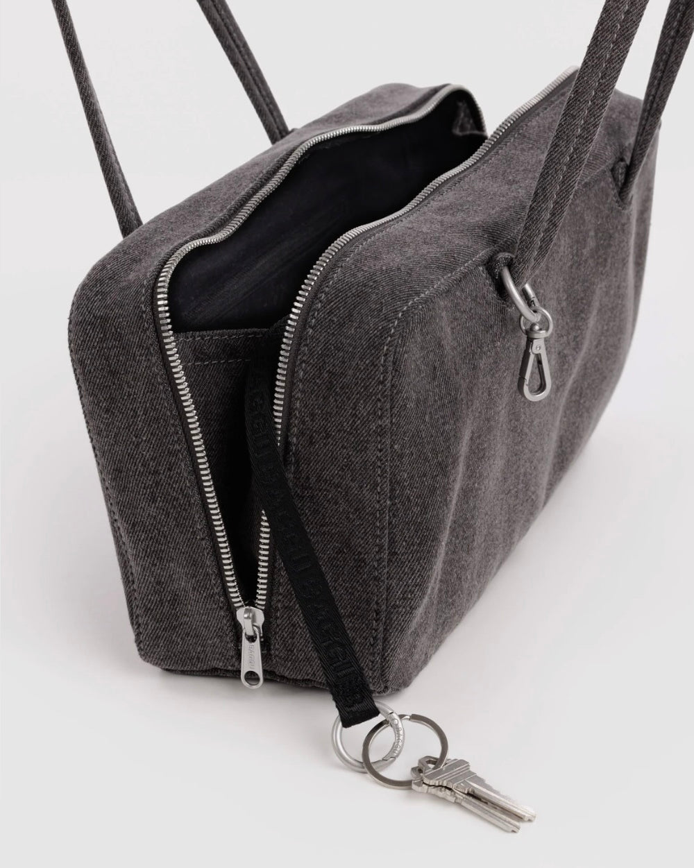 A dark gray woven fabric crossbody bag with silver zippers, a black strap, and a keychain attachment, shown on a clean white background.