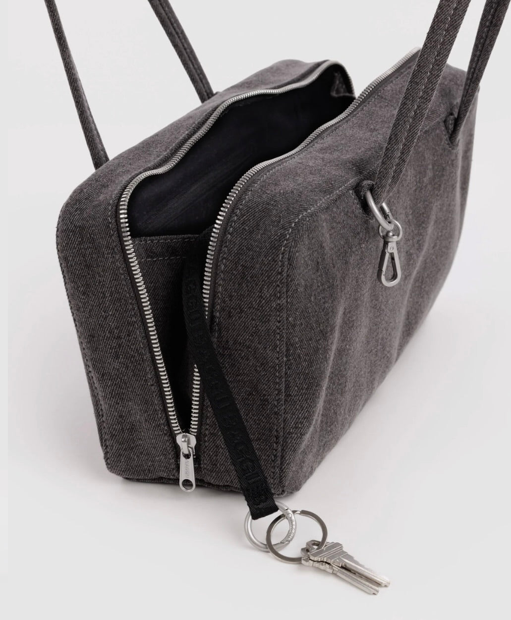 A dark gray woven fabric crossbody bag with silver zippers, a black strap, and a keychain attachment, shown on a clean white background.