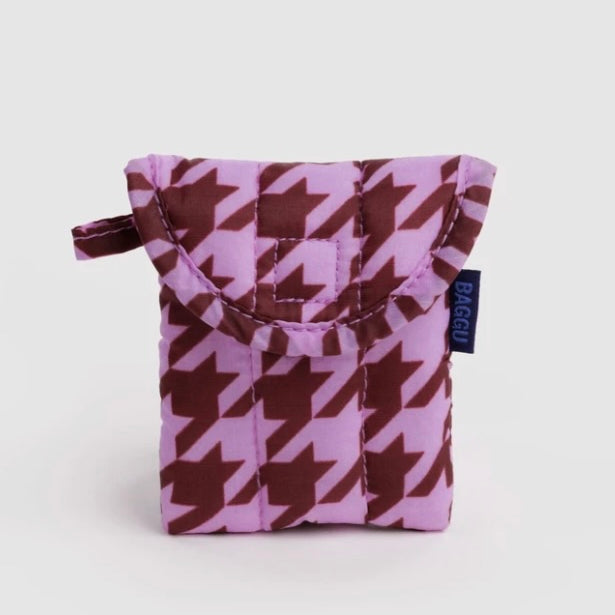 A small quilted pouch with a purple and brown houndstooth pattern, featuring a top handle and a small navy blue tag with the brand name BAGGU.