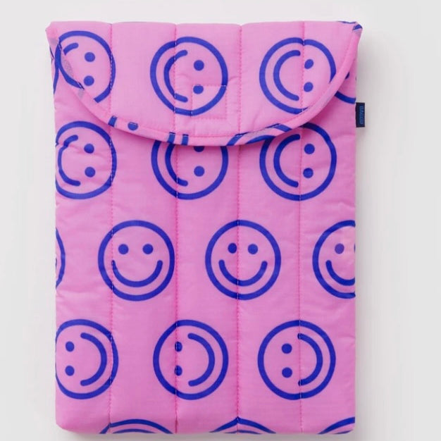 A pink quilted tablet sleeve featuring a repeating blue smiley face pattern, shown flat against a light gray background.