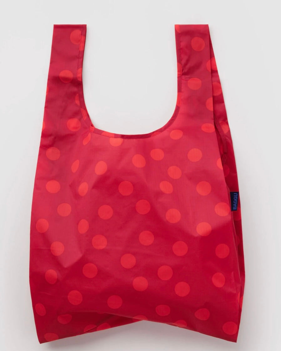 A reusable folding shopping bag in red with a pattern of darker red polka dots, shown against a plain light gray background.