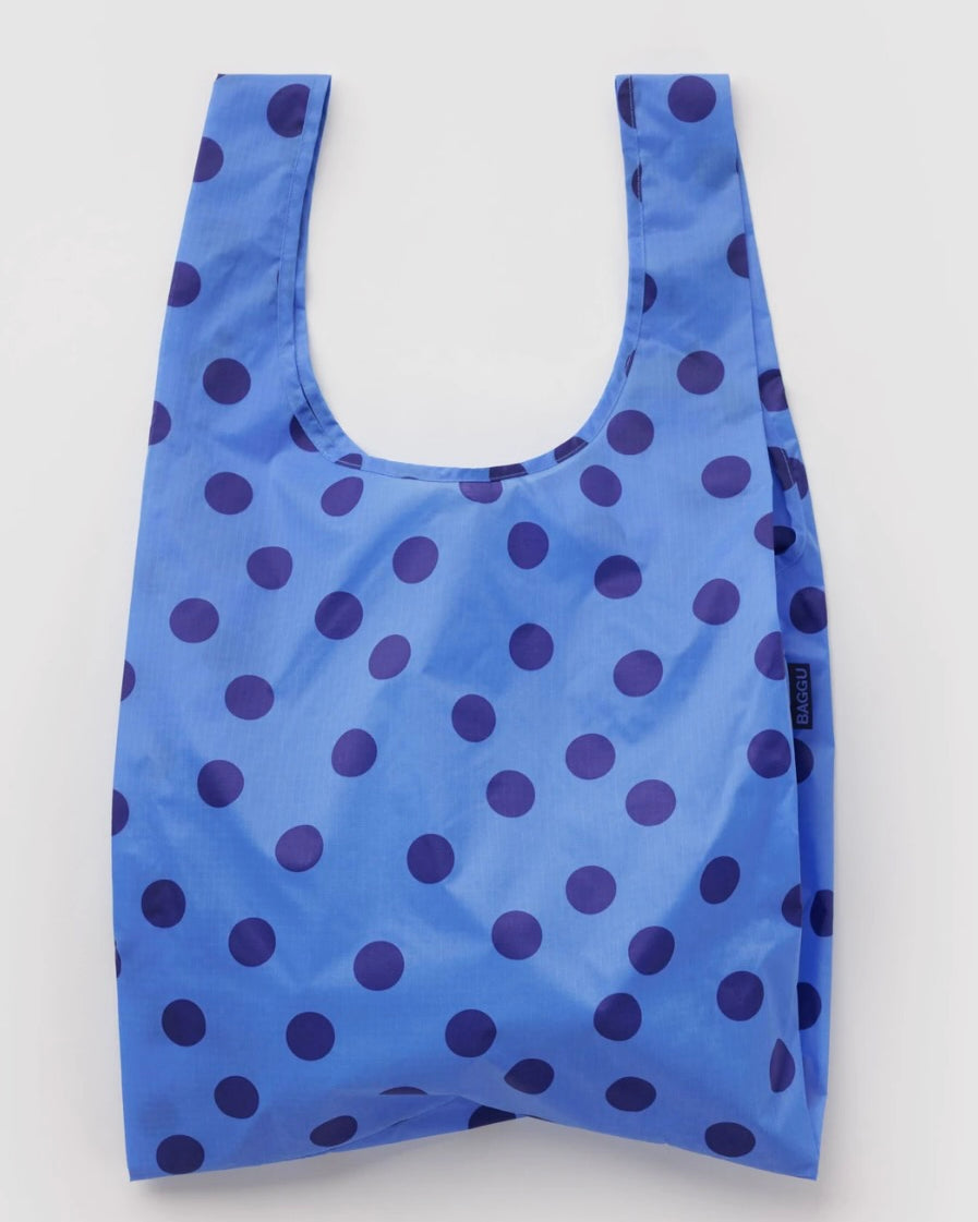 A reusable plastic shopping bag with a blue and dark purple polka dot pattern, shown against a plain light gray background.