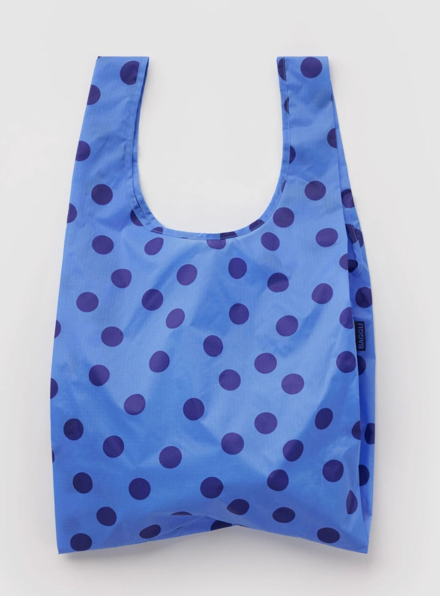 A reusable plastic shopping bag with a blue and dark purple polka dot pattern, shown against a plain light gray background.