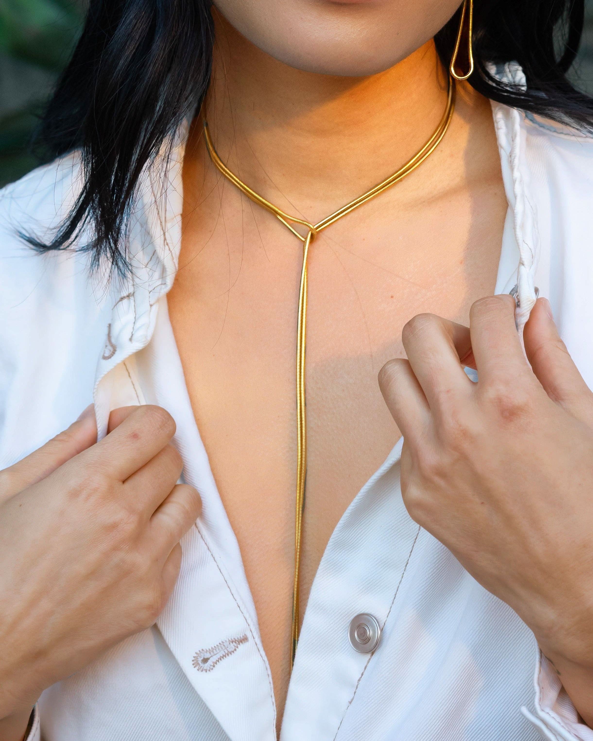 Person wearing a gold necklace with a white shirt