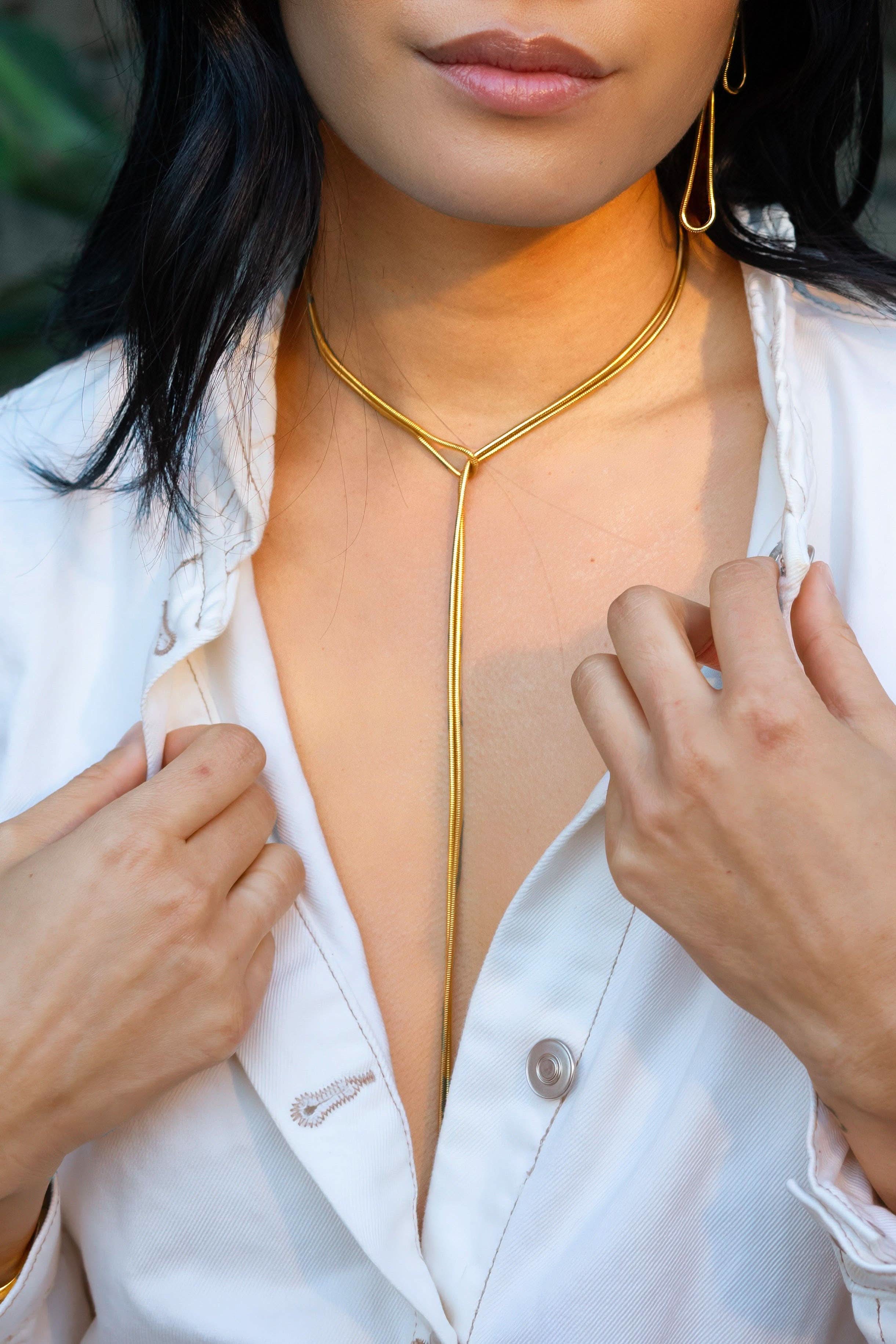 Person wearing a gold necklace with a white shirt
